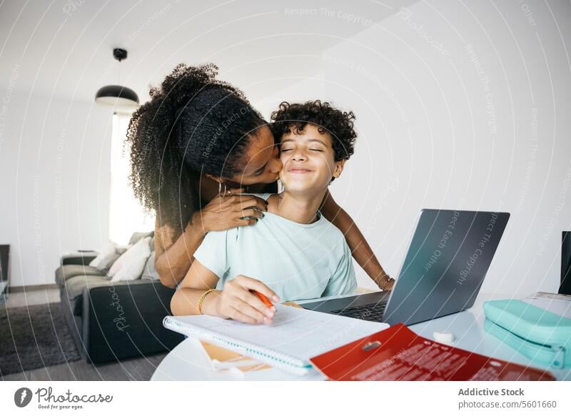 Girl doing her homework with mother Culture Family adorable affectionate after school bonding book cheerful child childhood children cute daughter day
