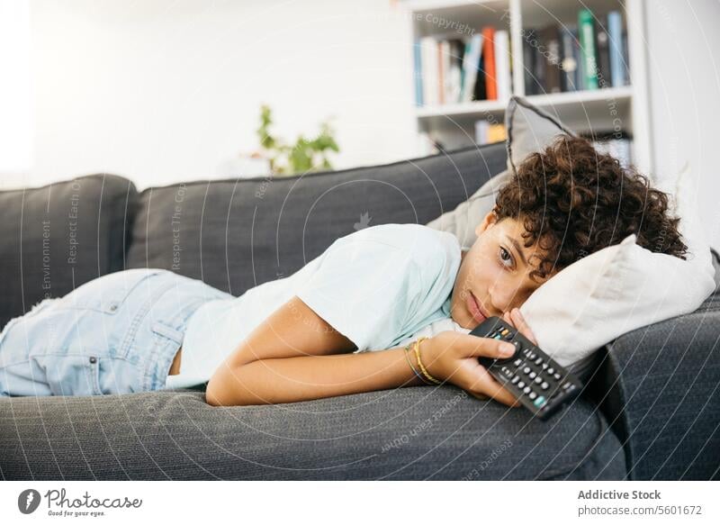 Girl watching tv in living room Family Preteen daughter Tv Tv controller adorable bored cheerful child childhood children couch cute female fun girl happiness