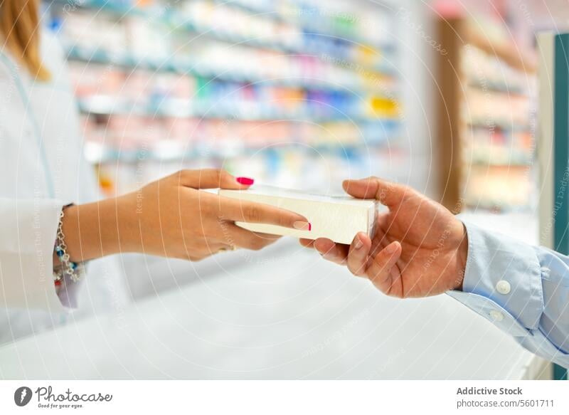 Woman giving product to customer in drugstore cashier woman hand crop anonymous checkout counter pharmaceutical shop seller box package holding receive owner