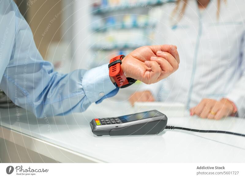 Man scanning smartwatch over machine and paying in store senior man pos terminal payment checkout counter drugstore hand crop anonymous modern retail client buy