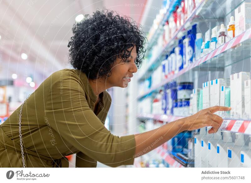 Woman searching medicines from shelves in store customer woman product shelf drugstore confident crouching aisle pharmacy buy shopper health care purchase