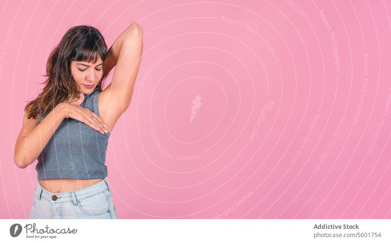 Woman doing a Breast Self-Exam over pink background. Copy space BSE Breast Cancer Awareness Breast Cancer Month Breast cancer prevention Breast health Mammogram