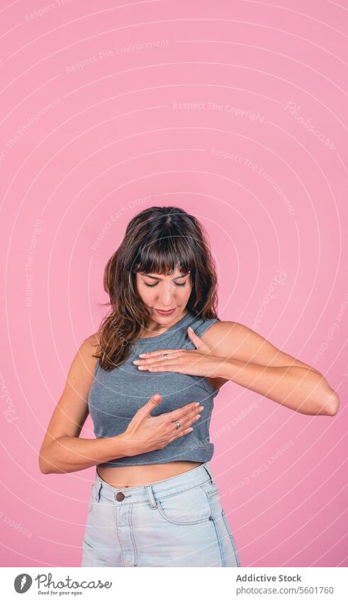 Woman doing a Breast Self-Exam checking up breast changes over pink background. Copy space BSE Breast Cancer Awareness Breast Cancer Month