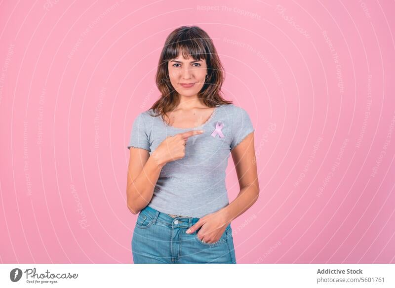 A woman pointing to a pink breast cancer awareness ribbon on her t-shirt. Breast Cancer Awareness Breast Cancer Month Breast cancer prevention Breast health