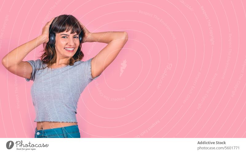 Happy woman in headphones listening to music isolated on pink background. Studio shot. Copy space Modern Wireless Technology adult attractive beautiful casual