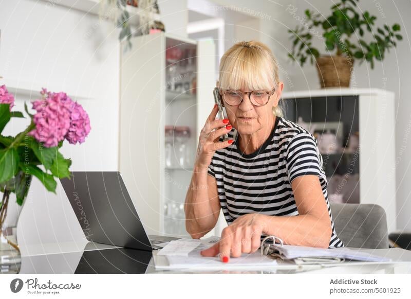 Worried old woman reading papers and having phone conversation at living room at home Copy Space Woman accounting aged banking bill budget buying call caucasian