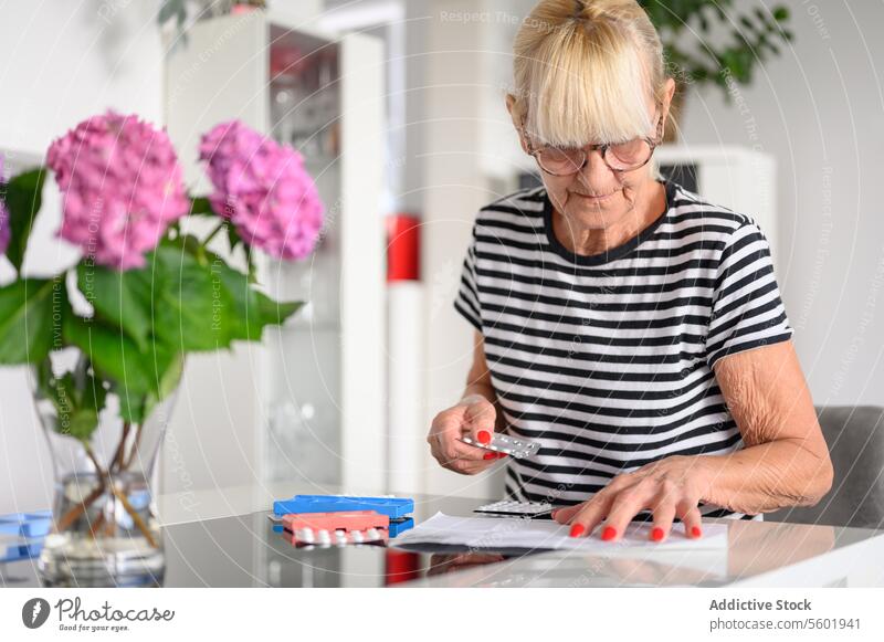 Senior woman preparing pill box at home read senior medicine glasses examine patient focus female medication elderly prepare concentrate aged drug medical
