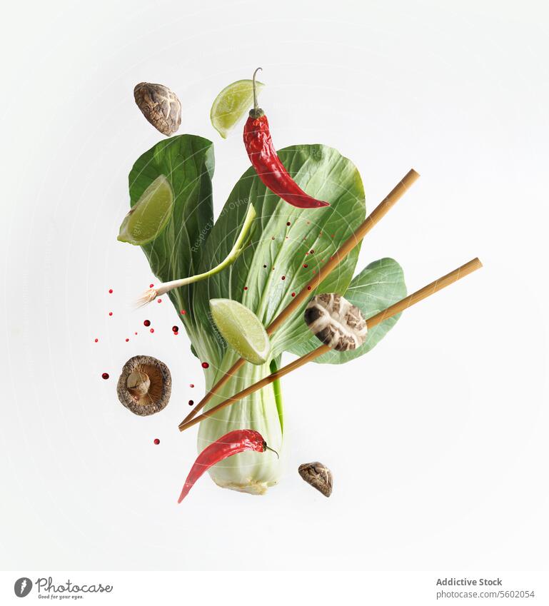 Asian food concept with flying ingredients: Bok choy , chopsticks, lime, shiitake, spices and chili  at white background. Levitation  food. Front view.