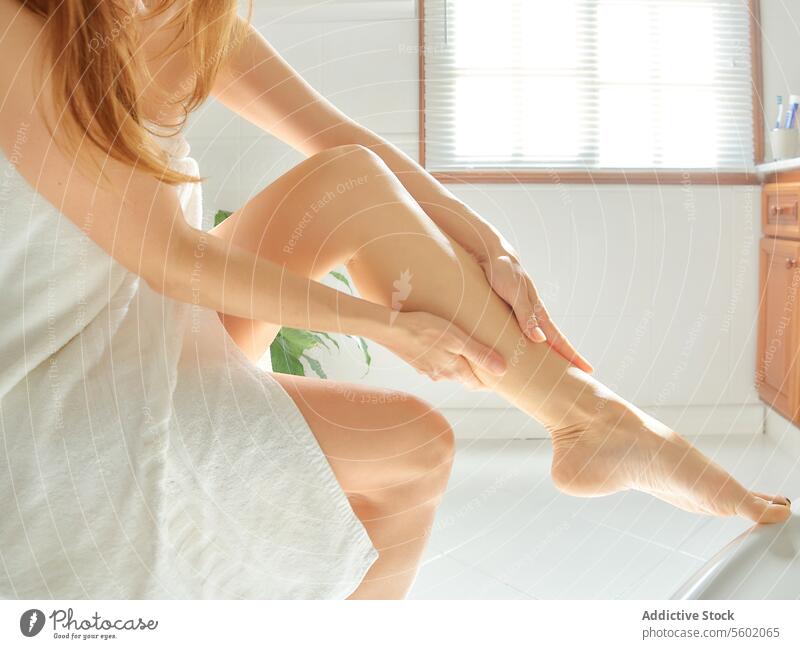 Wellness and skin care concept. Young woman massaging her legs after depilation in the bathroom. shave body home girl spa using wellness moisturizing cream