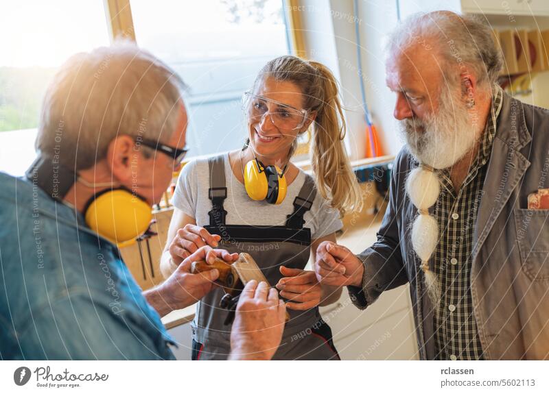 Generations of carpenters in their family business workshop discussing how to use a hand plane education earmuffs safety glasses protection apprentice wood