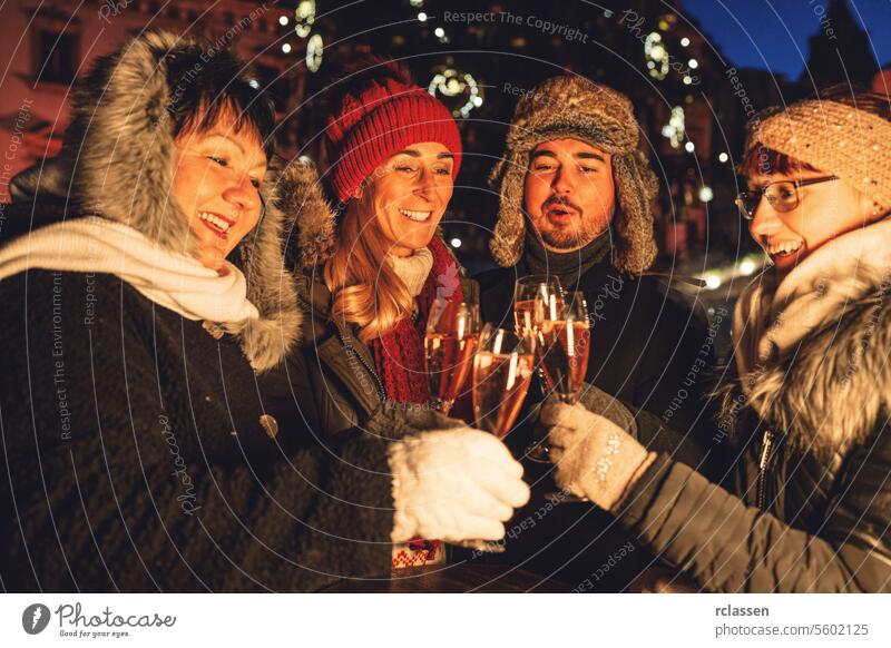 Group of friends toasting with champagne on a festive night on a christmas market event group new year couple winter evening glasses celebration happy joy
