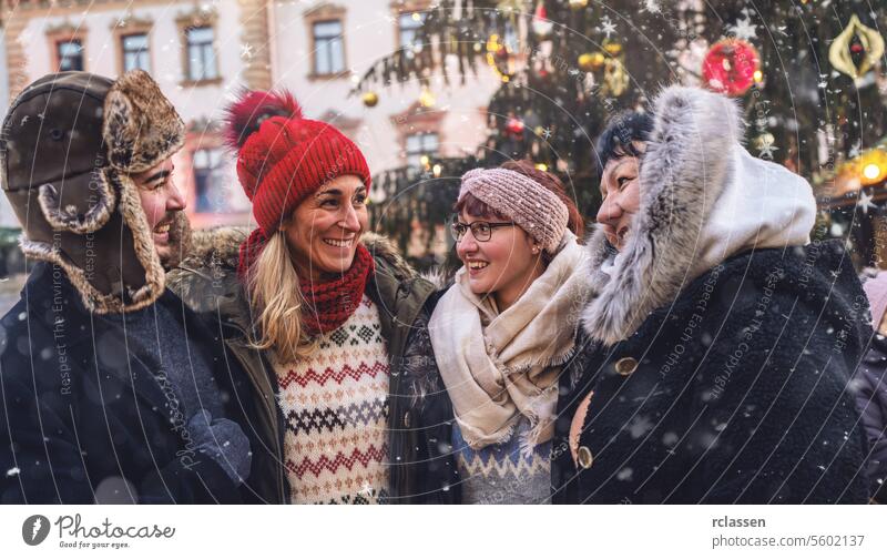 Friends laughing together at a snowy Christmas market meeting merry christmas cup hot chocolate gloves traditional mulled wine christmas market advent german