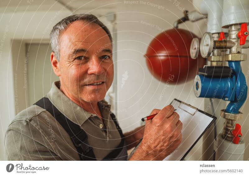 Engineer controlling the heating pipes at the gas boiler room with checklist on a Clipboard. Gas heater replacement obligation concept image clipboard