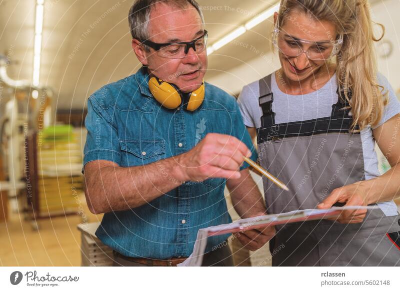 man and a woman reviewing a document in a carpentry workshop professional craftsman furniture industry reviewing document ear protection teamwork collaboration