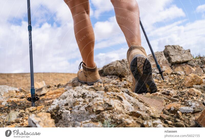 Close-up of hiker's legs with trekking poles walking on rocky trail fuerteventura adventure outdoor activity hiking boots nature close-up mountain hiking