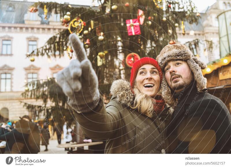 Surprised woman pointing with her hand to show her Boyfriend something on Christmas market at winter time in germany hand pointing new year drink xmas food