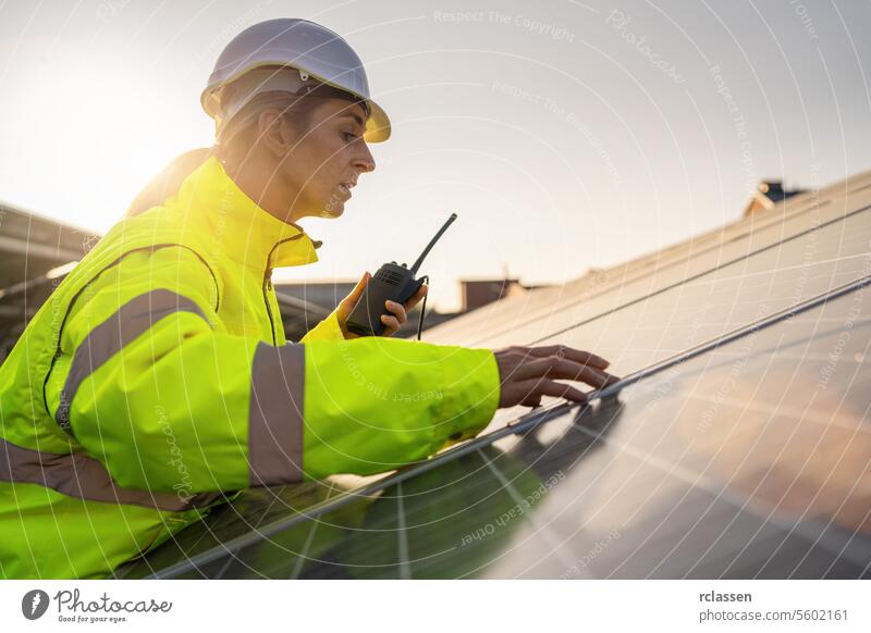 Solar technician with walkie-talkie inspecting solar panels at dusk. Alternative energy ecological concept image. master engineer modern technology plant