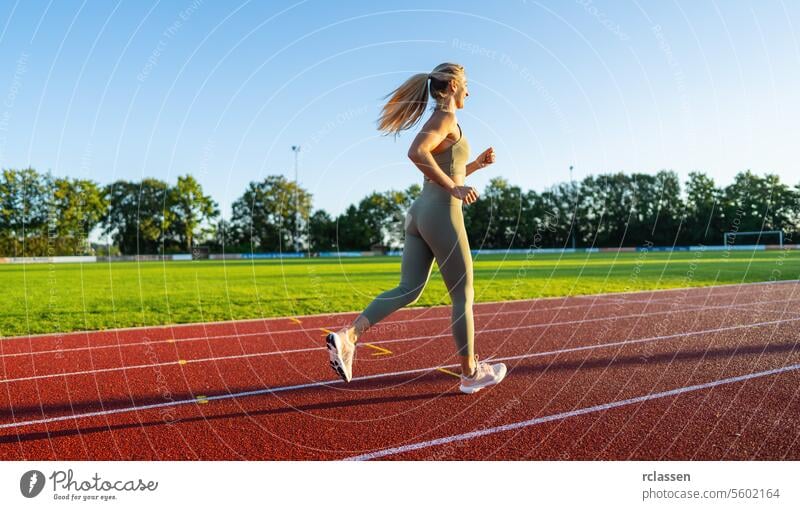 Side view of a woman running on a track in the sunlight event speed jogging athlete sports healthy lifestyle athletic wear running shoes outdoor exercise
