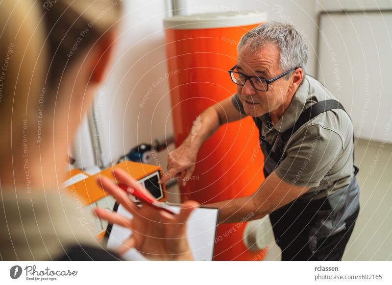 Team of heating engineers checks a old gas heating system at a boiler room in a house. Gas heater replacement obligation concept image clipboard woman teamwork