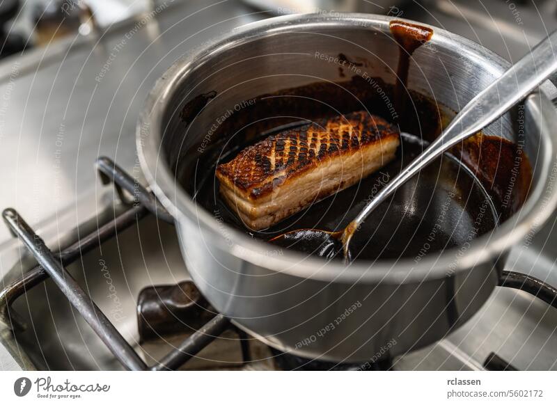 Crispy roasted pork glazed with brown sauce in a pot at a professional kitchen at a restaurant. Luxury hotel cooking concept image. kitchen equipment