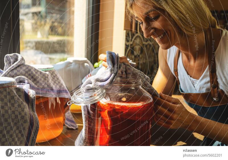 Happy Woman looking on kombucha tee with mushroom layers in a large jar. organic healthy drink fermented food, Probiotic nutrition drink for good balance digestive system.