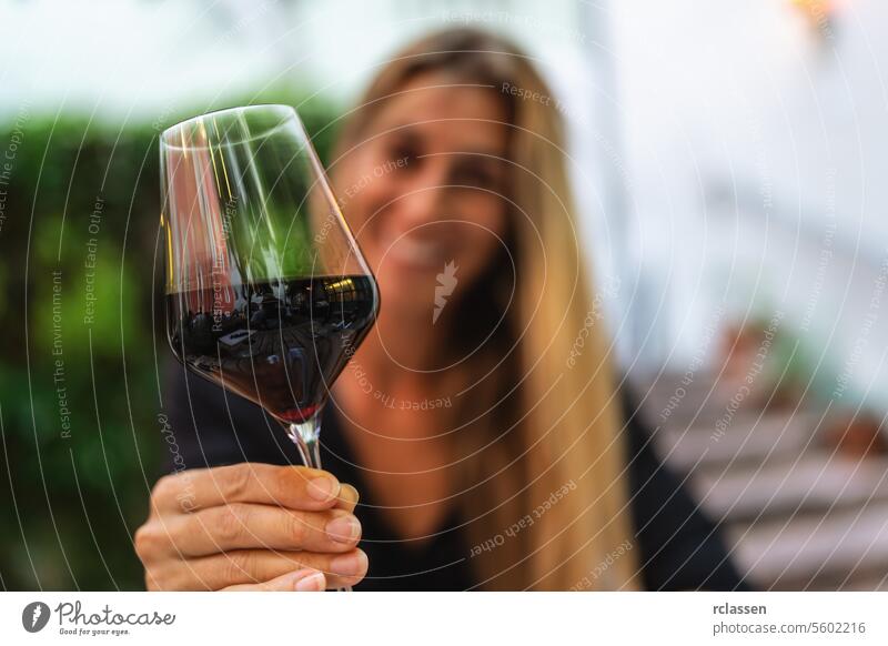 Woman toasting with a glass of red wine, blurred background restaurant dinner clinking glasses italy summer time woman wine tasting celebration cheers happy