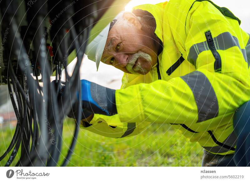Elderly worker in high visibility jacket inspecting cables. Alternative energy ecological concept image. engineer solar park technology plant industry