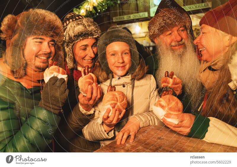 Family enjoying sausages at a Christmas market, smiling together with winter hats merry christmas gloves traditional mulled wine christmas market advent german