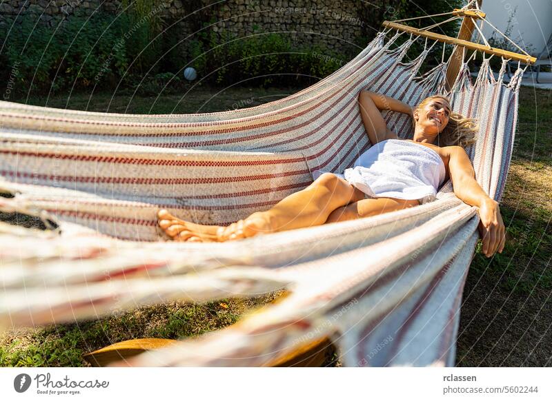 woman relaxing in a hammock outdoor after sauna in spa resort hotel finnish towel thermal bathrobe beauty body treatment skin health clean girl care skincare