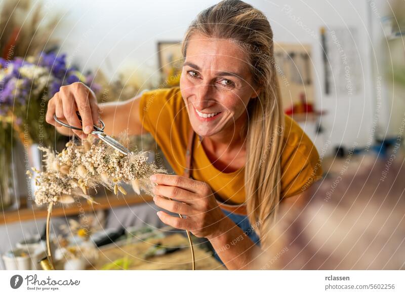 smiling florist woman trims a delicate dried flower arrangement, working meticulously in a studio filled with floral elements happy customer shop