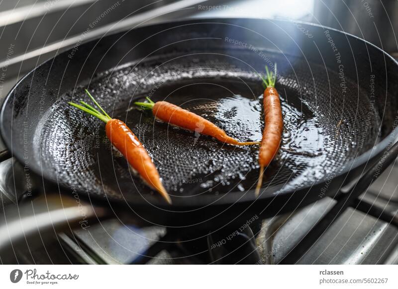 Fresh carrots frying in oiled pan at a gas stove in a professional kitchen at a restaurant. Luxury hotel cooking concept image. vegetables skillet sautéing