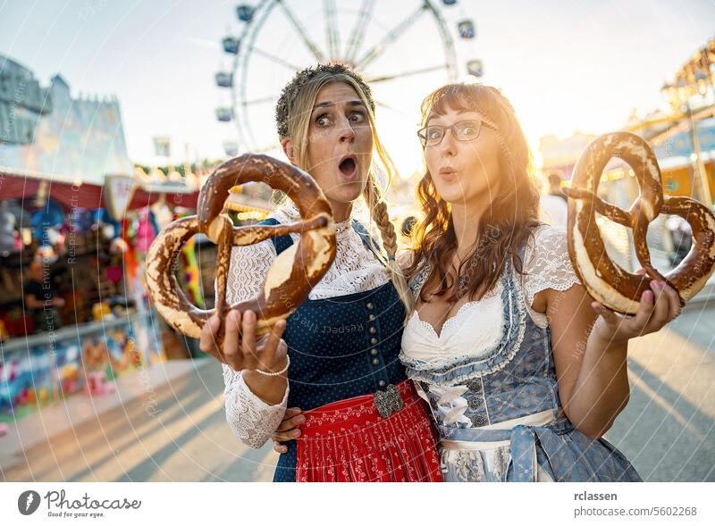 Two happy girlfriends together on a Bavarian fair or oktoberfest or duld in national costume or Dirndl with  pretzel or brezen in germany woman party beergarden