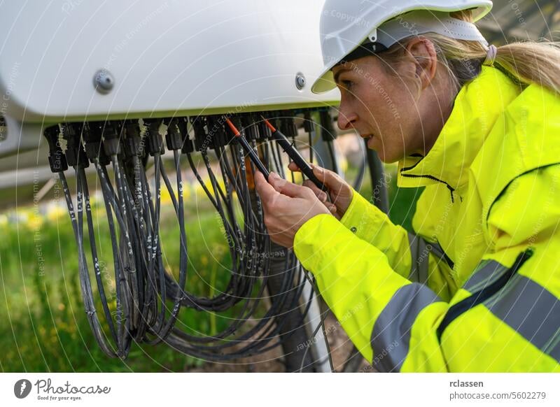 Technician checking solar panel cables with a multimeter in a solarpark field. Alternative energy ecological concept image. technology plant industry