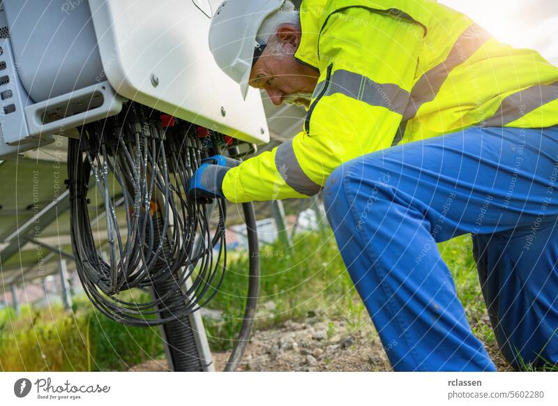 Engineer at a distribution station in a solar panel park handling cables. Alternative energy ecological concept image. electricity worker industry engineer