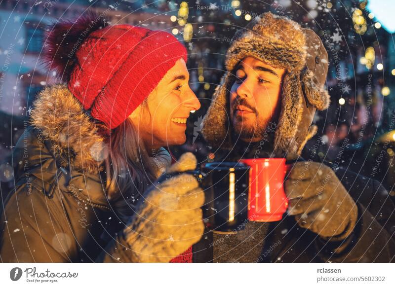 Couple toasting with mulled wine at a Christmas market punch cup hot chocolate gloves traditional christmas market advent german snowflakes holiday xmas lights