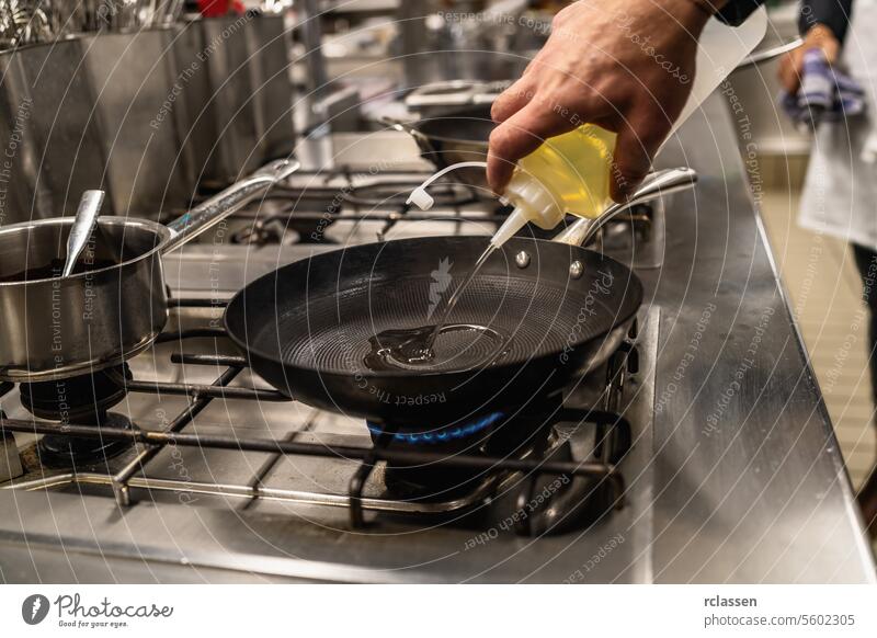 Chef cook pouring Oil into a Heated Skillet. Luxury hotel cooking concept image. hand cuisine chef oil pouring skillet professional kitchen stovetop