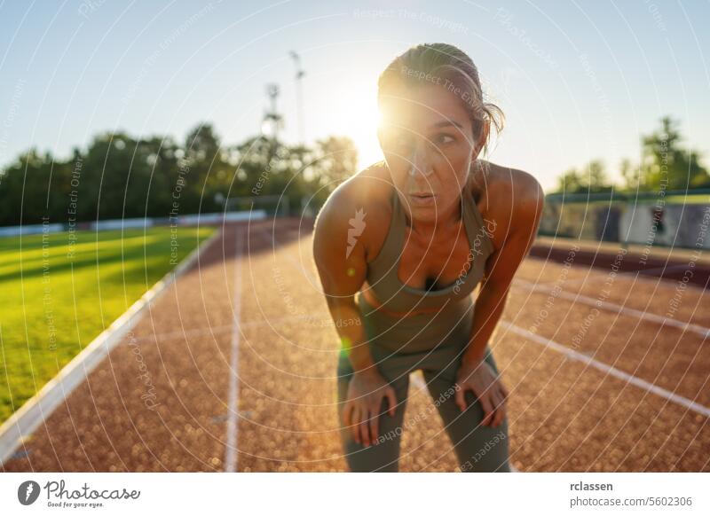 Exhausted woman resting on a running track after workout exhausted fitness sport training athlete tired active wear exercise outdoor sunset healthy lifestyle