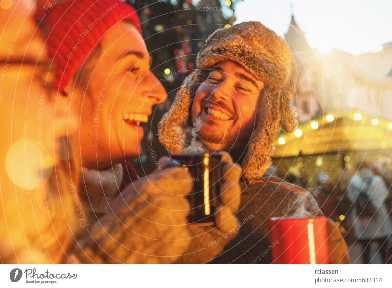Happy friends having fun drinking mulled wine and hot chocolate at Christmas Market - Cheerful young people enjoying winter holidays on weekend vacation