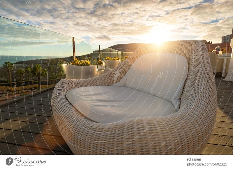 Wicker lounge chair on a hotel deck at sunset with ocean and mountain views ocean view wicker furniture relaxation luxury leisure outdoor furniture comfort
