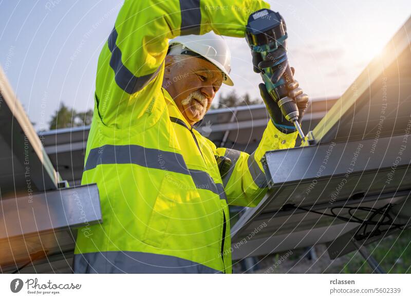 Engineer using a cordless drill to install solar panels at dawn. Alternative energy ecological concept image. master engineer renewable resource professional