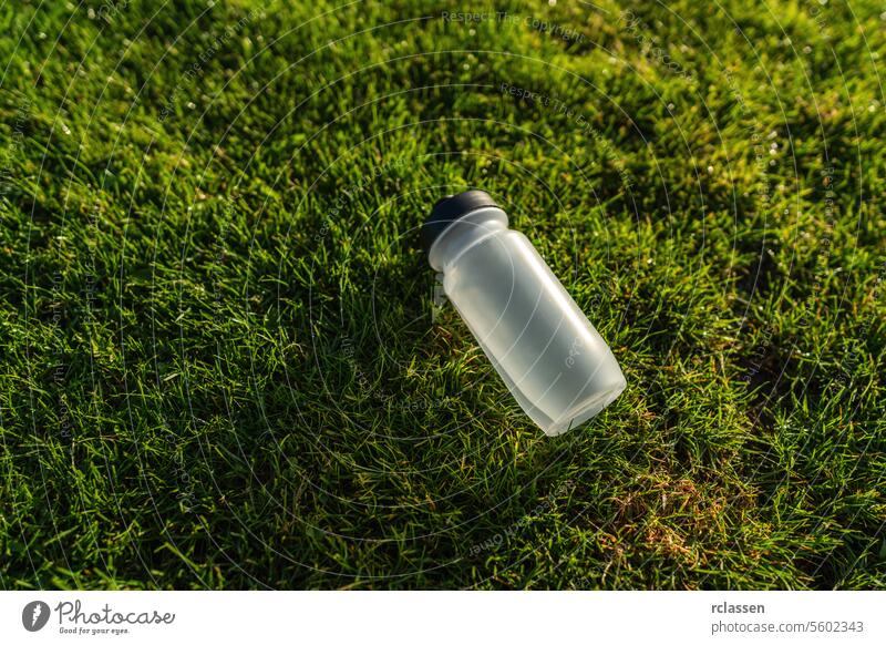 Water bottle lying on the grass in sunlight. Sports gear concept image water bottle hydration fitness green health wellness outdoor exercise training