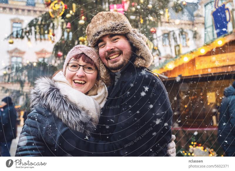 Happy couple hugging at a snowy Christmas market, smiling joyfully friends mulled wine boyfriend beard tourism dating fair travel happy love new year