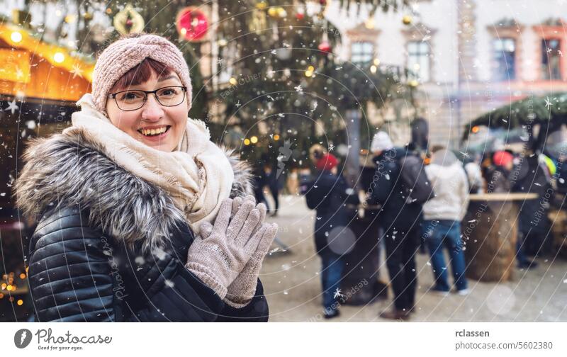Young woman enjoying a snowy Christmas market, wearing winter clothes and a beanie, smiling in camera with copyspace for your individual text. tourist