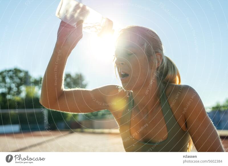 Woman pouring water on face after workout, sun flare, sports bottle, refreshing woman athlete hydration exercise cooling down heat outdoor fitness sportswear