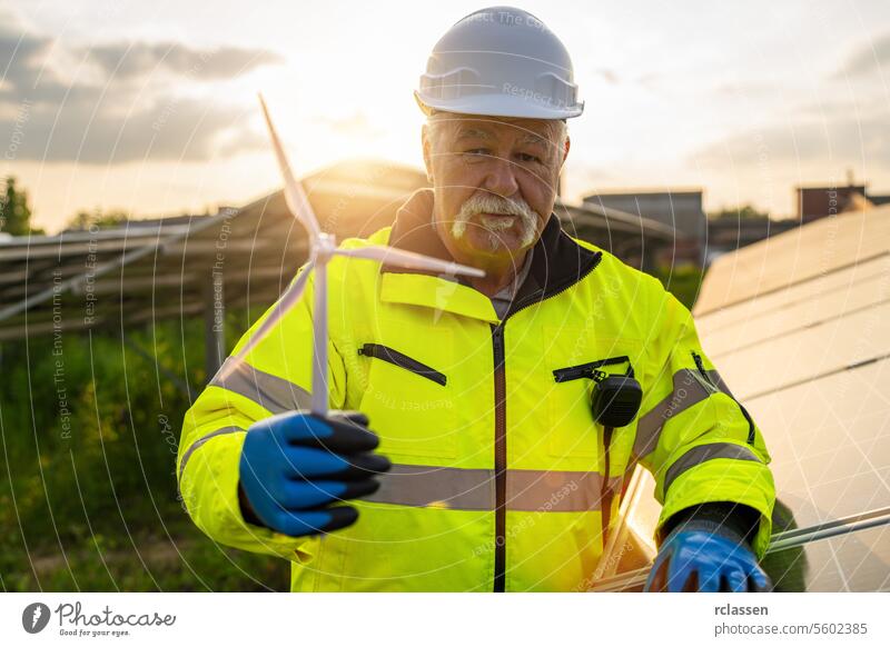 Senior engineer holding a wind turbine model at a solar plant. Alternative energy ecological concept. technology industry electricity worker safety ecology