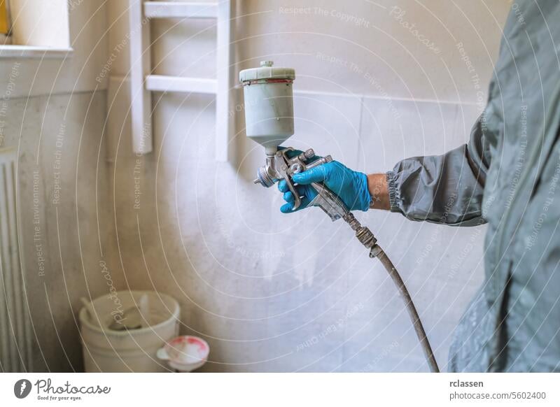 Worker using a spray gun to paint, wearing safety gloves and protective clothing master holding car paint carpenter craftsman mask painter worker paintwork