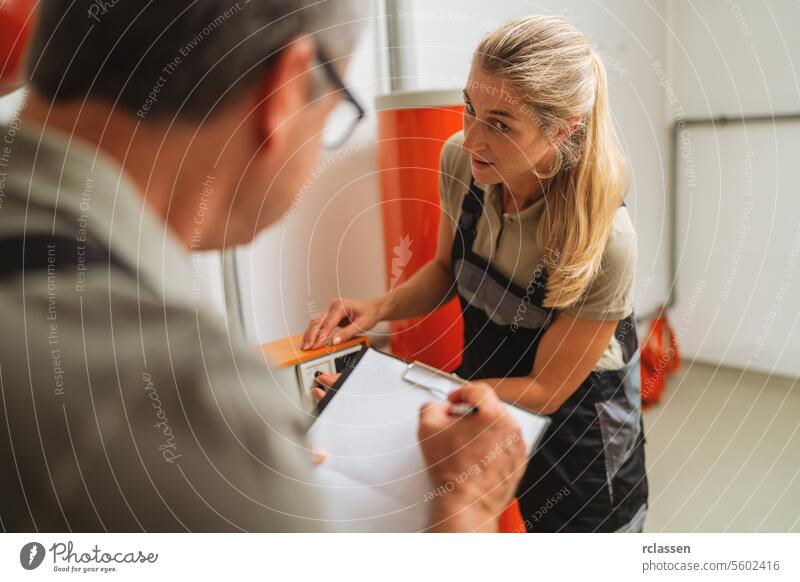Team of heating engineers discussing and checking a old gas heating system, holding a Clipboard with checklist at a boiler room in a house. Gas heater replacement obligation concept image