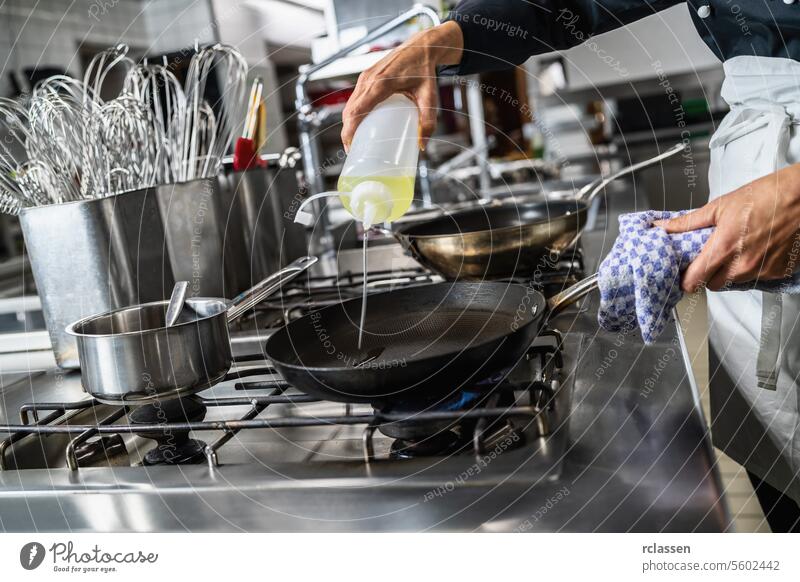 cook pouring Oil into a Heated pan at a restaurant. Luxury hotel cooking concept image. hand cuisine chef oil pouring skillet professional kitchen stovetop