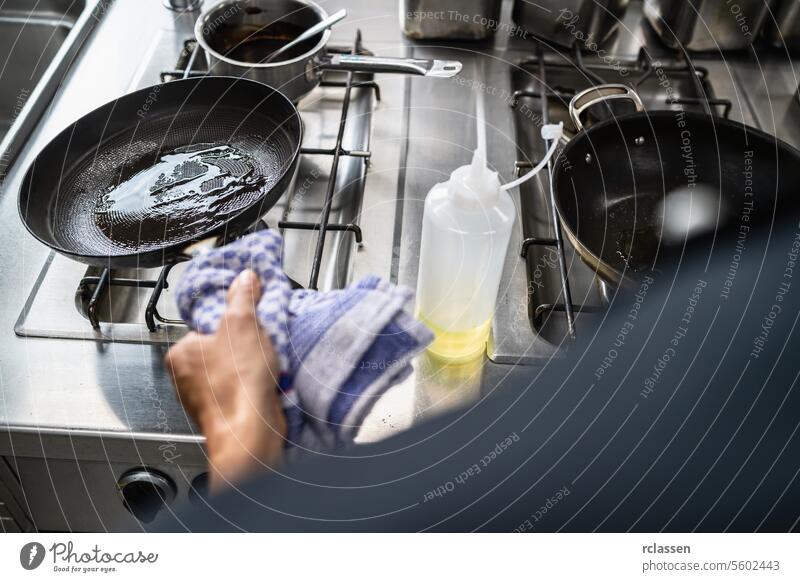 Chef cook swings Oil a Heated Skillet at restaurant. Luxury hotel cooking concept image. hand cuisine chef oil pouring skillet professional kitchen stovetop