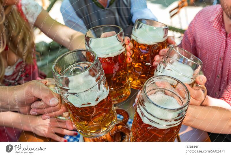 Group of happy friends drinking and toasting beer at Oktoberfest in bavaria brezen german bavarian bar celebration cheers dirndl lager hangout party pup
